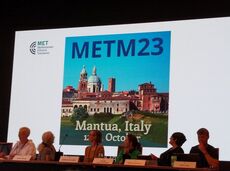 A group of people sitting in front of a screen with the message 'METM23 - Mantua, Italy'