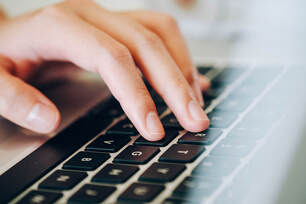Image of a hand resting on a laptop keyboard